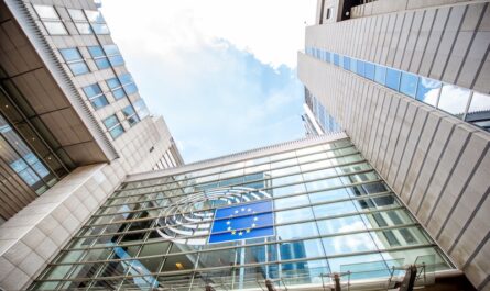 Moderne Glasfassade eines EU-Gebäudes mit dem Emblem der Europäischen Union und Blick nach oben zwischen Hochhausfassaden.